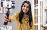 Influencer mulher jovem segura um celular em posição de selfie